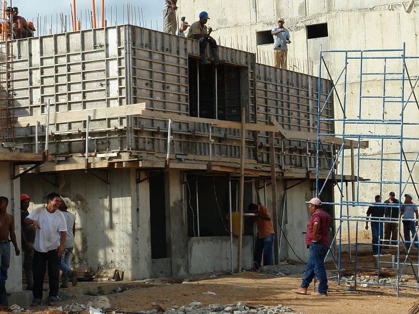 Concrete formwork, blue scaffolding and workers at a building site