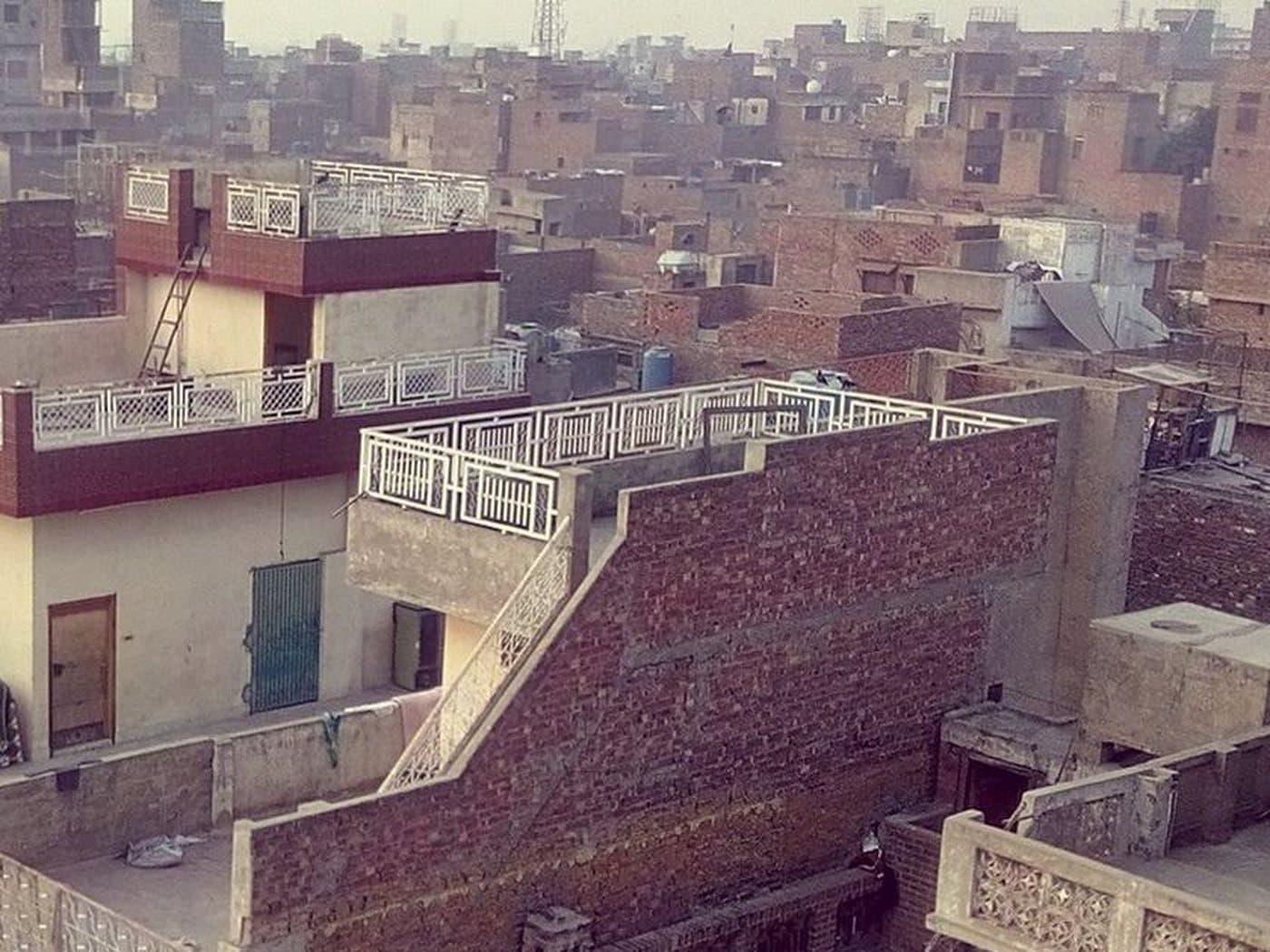 Brick and concrete rooftops with white railings and screens, seen from above