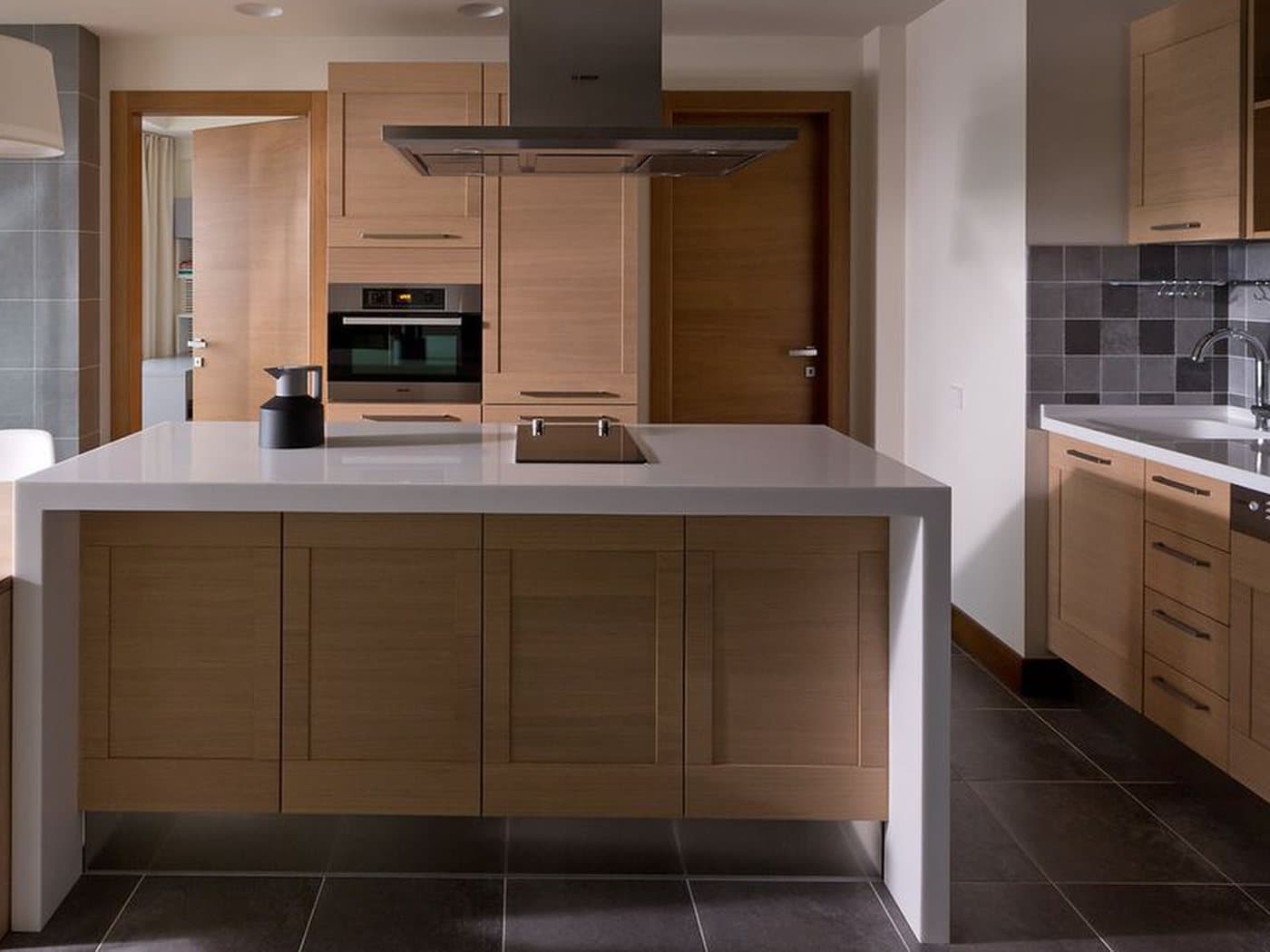 A kitchen island with a white worktop and timber cabinets